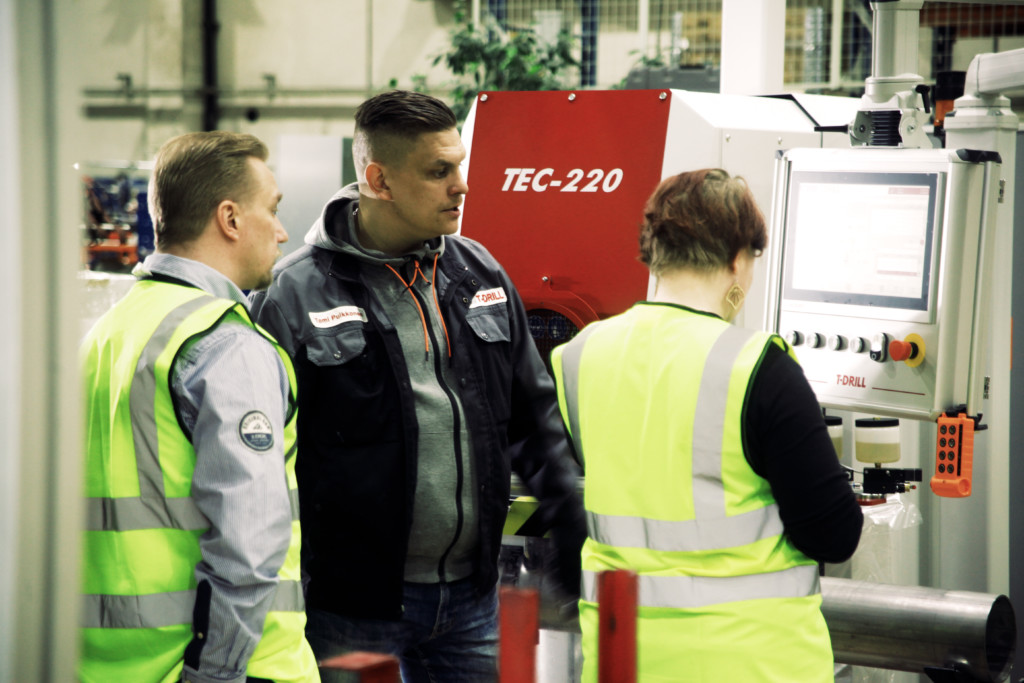 Three people looking at a collaring machine's screen