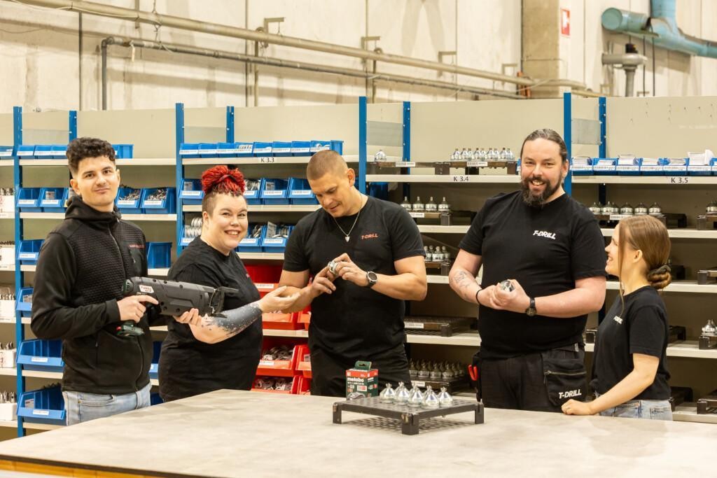 Smiling people holding tools and components in a warehouse